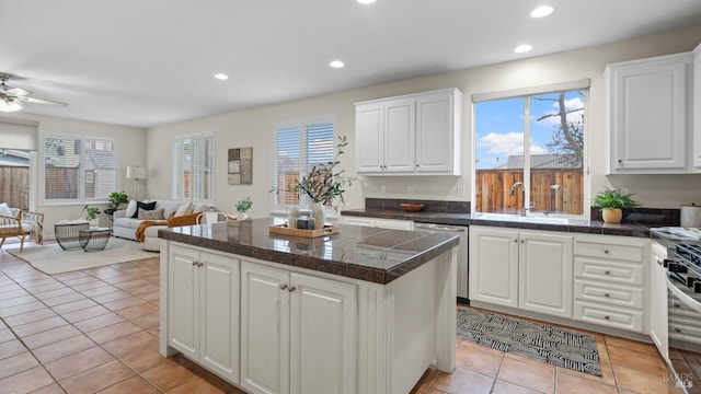 kitchen with a wealth of natural light, stainless steel dishwasher, a sink, and tile counters