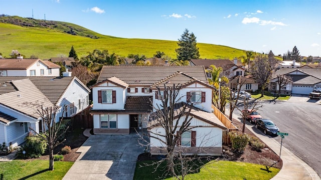 view of front of property featuring stucco siding, a residential view, a tiled roof, and concrete driveway