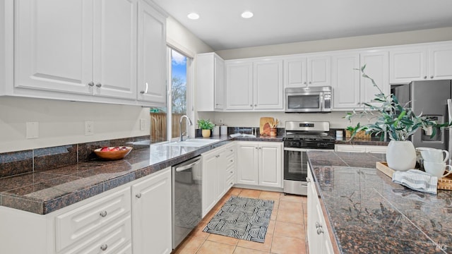 kitchen with stainless steel appliances, sink, light tile patterned floors, and white cabinets