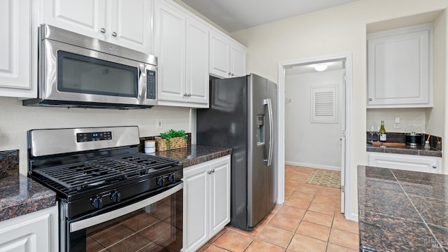 kitchen with tile countertops, light tile patterned flooring, white cabinets, baseboards, and appliances with stainless steel finishes