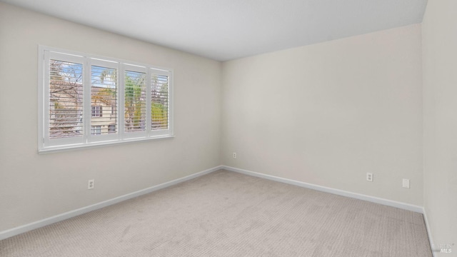 carpeted empty room featuring baseboards