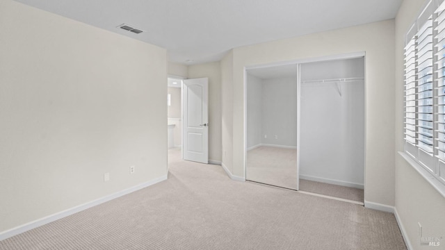 unfurnished bedroom featuring a closet and light carpet