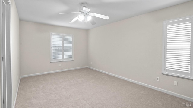 spare room featuring carpet, a wealth of natural light, a ceiling fan, and baseboards