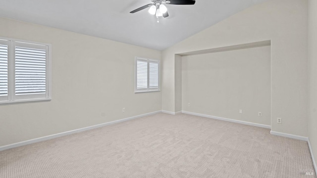carpeted empty room with vaulted ceiling, baseboards, and ceiling fan