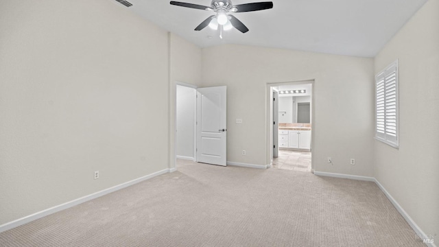 unfurnished bedroom with baseboards, light colored carpet, lofted ceiling, a ceiling fan, and ensuite bath