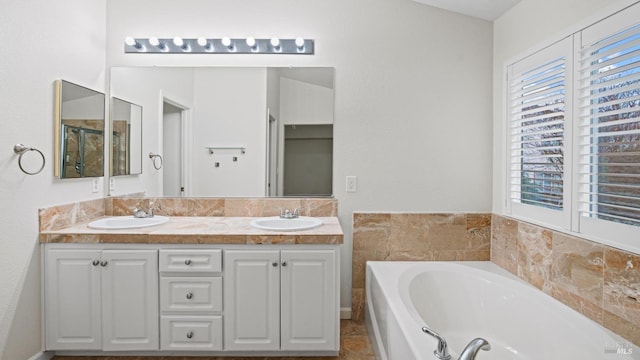 bathroom with a bath, a sink, and double vanity