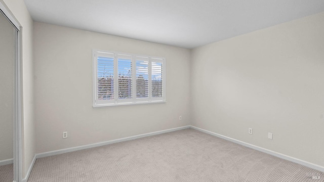 carpeted empty room featuring baseboards