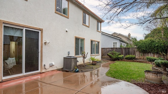 back of house with a fenced backyard, central AC, a yard, a patio, and stucco siding