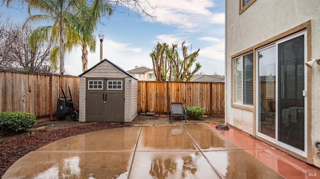 view of patio / terrace with a fenced backyard, a storage unit, and an outdoor structure