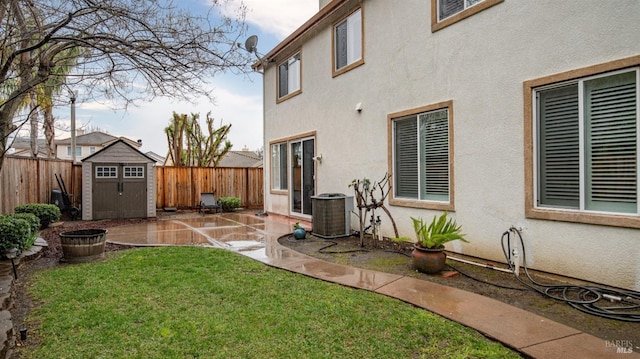 back of house featuring central AC unit, a fenced backyard, a shed, stucco siding, and an outbuilding