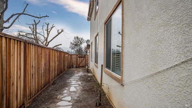 view of side of home featuring stucco siding and fence