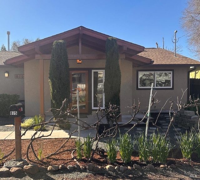 view of front of house featuring a shingled roof and stucco siding