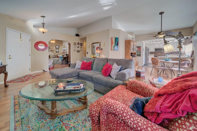 living room with lofted ceiling, ceiling fan, and light wood-type flooring