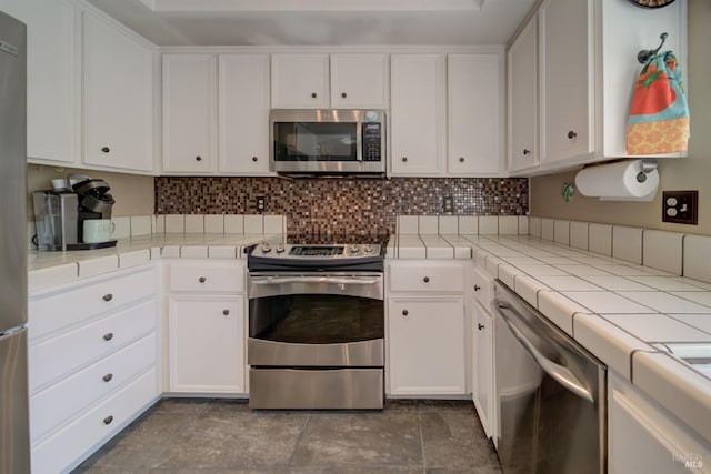 kitchen with white cabinetry, stainless steel appliances, tile counters, and backsplash