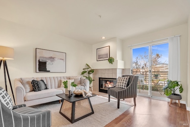 living room with plenty of natural light, a tiled fireplace, and light hardwood / wood-style floors