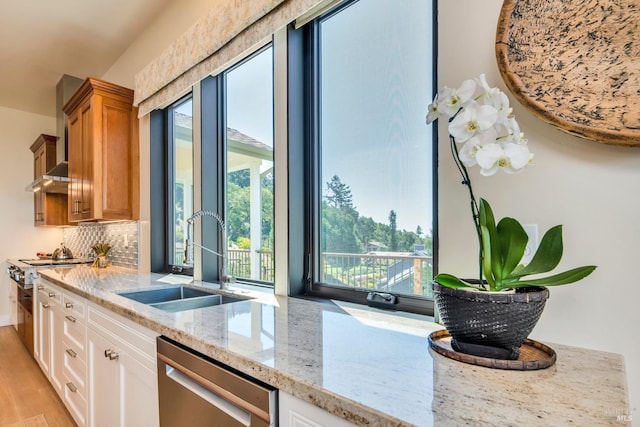 kitchen featuring dishwasher, light stone counters, a wealth of natural light, sink, and white cabinetry