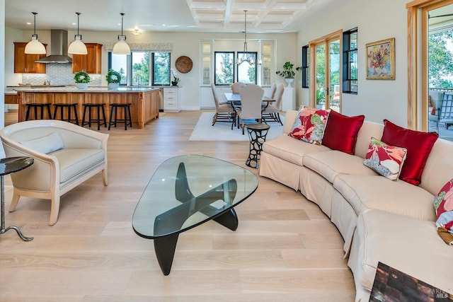 living room featuring coffered ceiling, light wood-type flooring, plenty of natural light, and beam ceiling