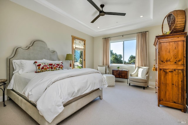 carpeted bedroom with ceiling fan and a tray ceiling