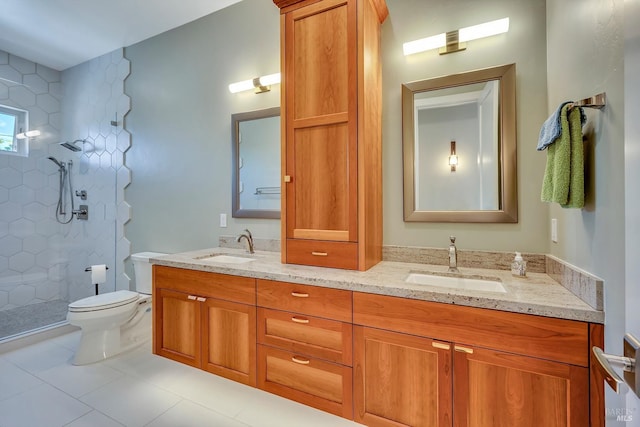 bathroom featuring tile patterned flooring, vanity, a tile shower, and toilet