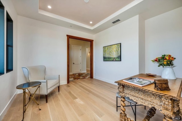 sitting room with light hardwood / wood-style flooring and a tray ceiling