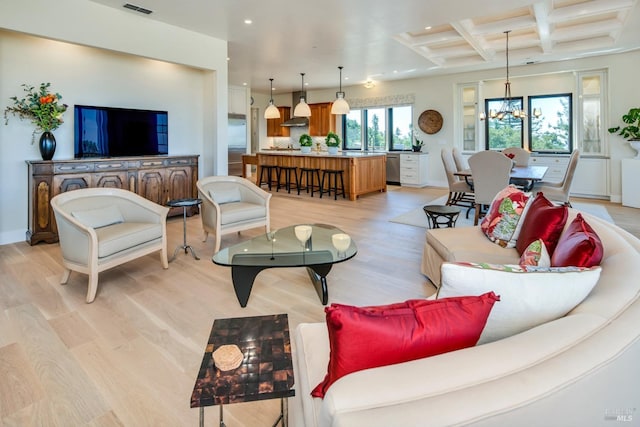 living room featuring coffered ceiling, beam ceiling, a chandelier, and light wood-type flooring