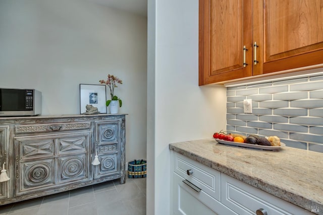 interior space with light tile patterned floors, tasteful backsplash, and light stone counters