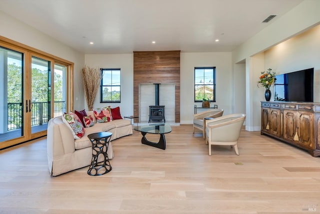 living room with a wood stove and light hardwood / wood-style flooring