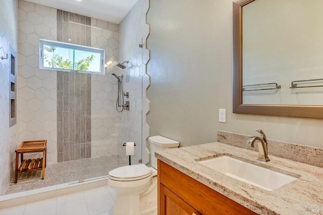 bathroom featuring a tile shower, vanity, tile patterned flooring, and toilet