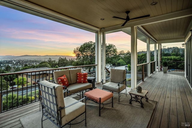 deck at dusk featuring ceiling fan and a mountain view