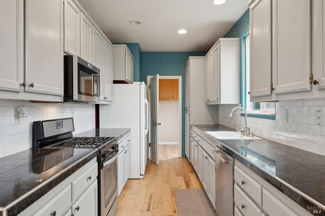 kitchen featuring appliances with stainless steel finishes, light hardwood / wood-style floors, sink, and white cabinets