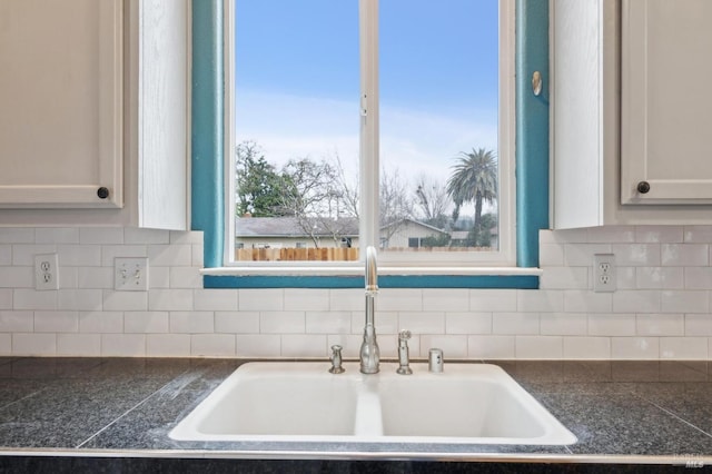 interior details with white cabinetry, sink, and tasteful backsplash