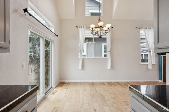 kitchen featuring a notable chandelier, light hardwood / wood-style flooring, gray cabinets, and a high ceiling