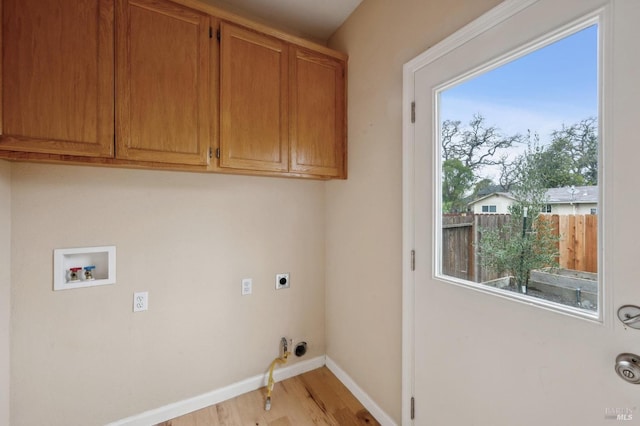 clothes washing area featuring hookup for a gas dryer, cabinets, light hardwood / wood-style floors, hookup for a washing machine, and hookup for an electric dryer