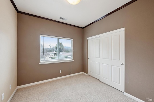 unfurnished bedroom with light carpet, crown molding, and a closet