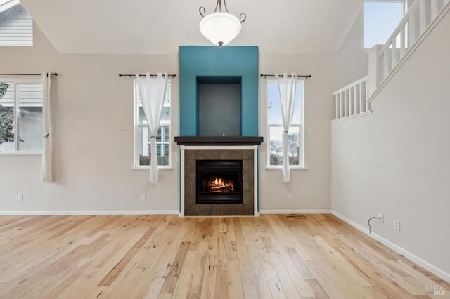 unfurnished living room featuring wood-type flooring and a tile fireplace