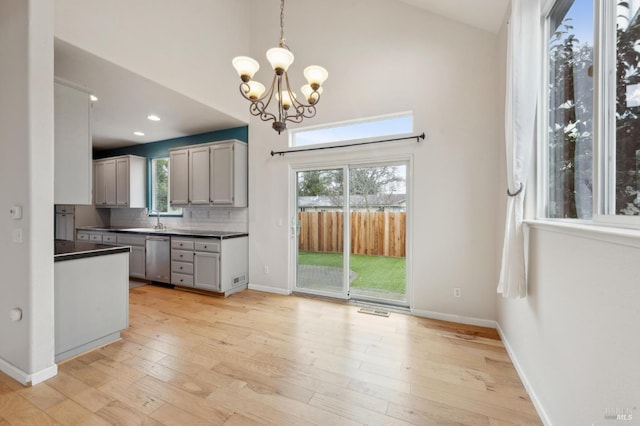 kitchen with sink, tasteful backsplash, decorative light fixtures, light wood-type flooring, and dishwasher