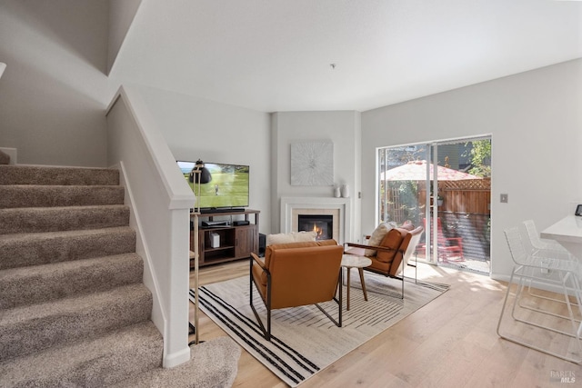 living room with a tiled fireplace and light hardwood / wood-style flooring