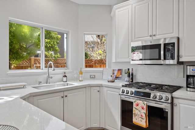 kitchen featuring tasteful backsplash, sink, white cabinets, and appliances with stainless steel finishes