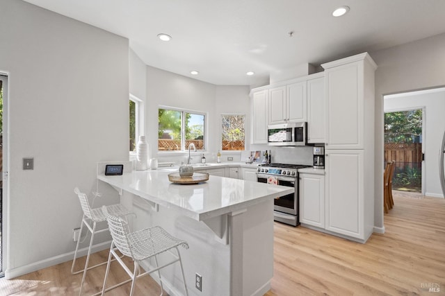 kitchen with white cabinetry, appliances with stainless steel finishes, a breakfast bar, and kitchen peninsula