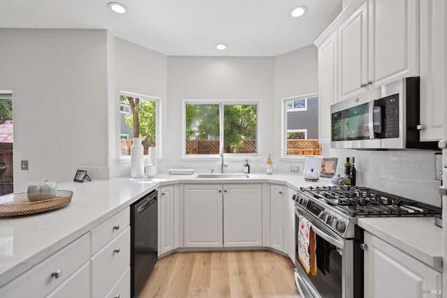 kitchen featuring light wood-type flooring, stainless steel appliances, sink, and white cabinets