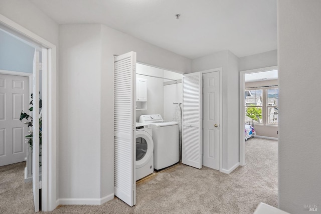 laundry area featuring cabinets, washer and dryer, and light colored carpet