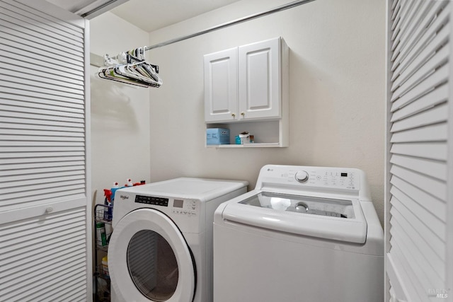 washroom featuring cabinets and washer and clothes dryer