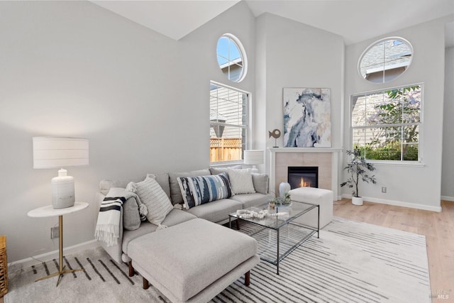 living room featuring a fireplace, high vaulted ceiling, and light wood-type flooring