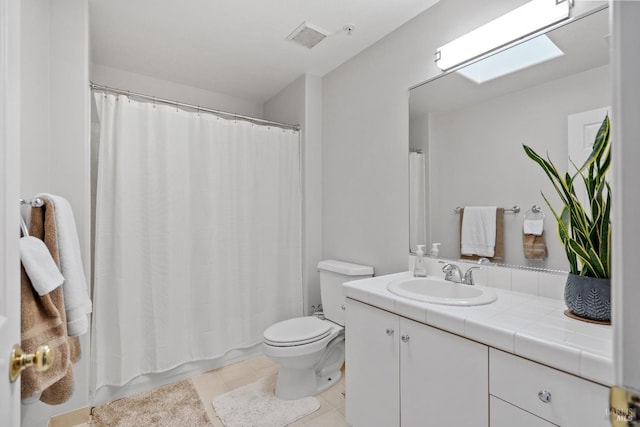 bathroom featuring vanity, tile patterned flooring, a skylight, and toilet