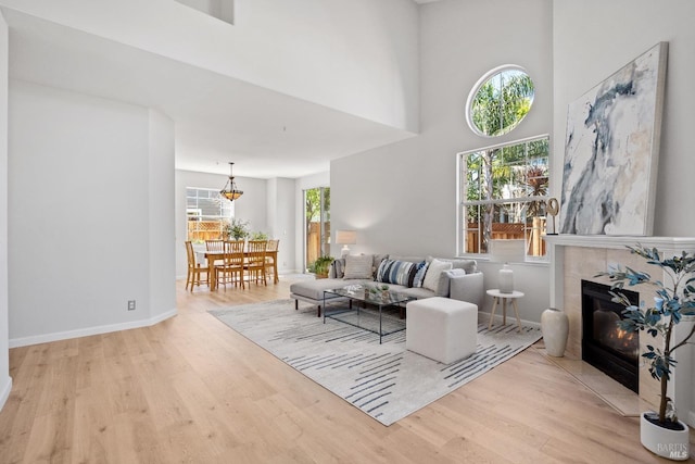 living room with a towering ceiling, light hardwood / wood-style flooring, and a tile fireplace