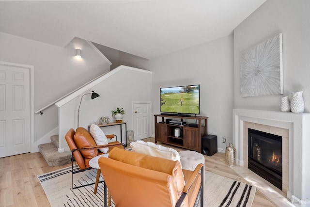 living room with a tile fireplace and light wood-type flooring