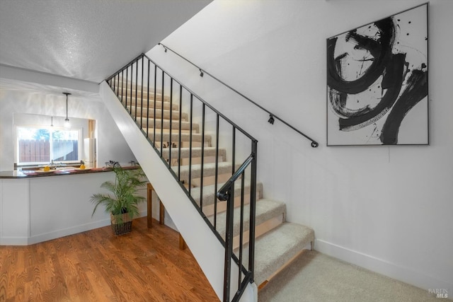 staircase with hardwood / wood-style floors and a textured ceiling