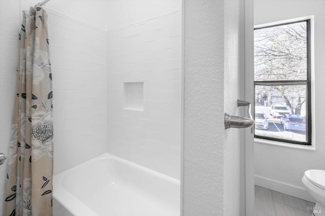 bathroom featuring toilet and shower / bathtub combination with curtain