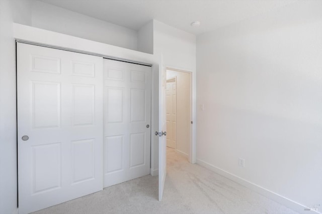 unfurnished bedroom with light colored carpet and a closet