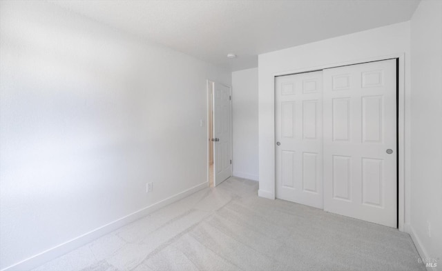 unfurnished bedroom featuring light colored carpet and a closet